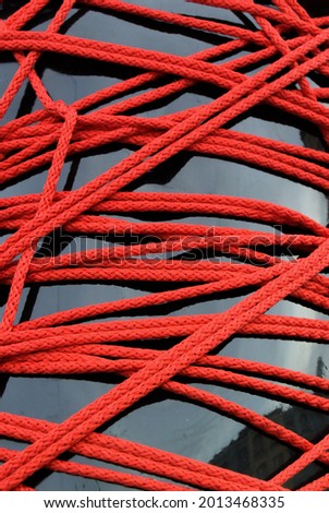 Photo of a background with a black female mannequin wrapped in red ropes.
