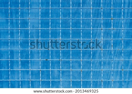 Metal mesh with square cells on blue painted background