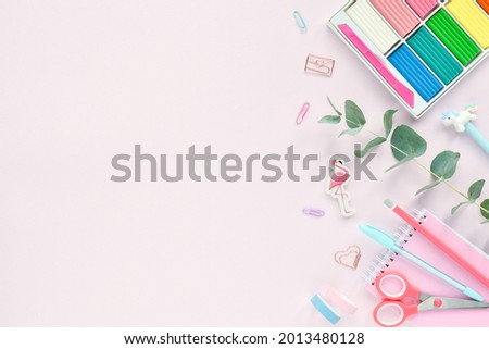 A frame of pastel-colored school supplies on a pink background, a place for text. Back to the school. Office supplies. Flat lay, top view, copy space.