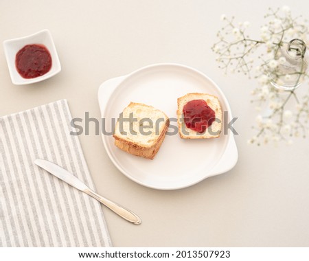 Having breakfast bread with strawberry jam