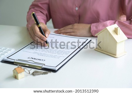 Real estate agent holding home and signing contract about agreement of real property on desk, businessman writing on document form rent house, house broker and planning investment,  business concept