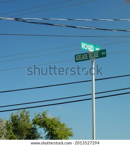 Street signs to Richard Drive and Adelaide Village Road in Nassau, with electric lines crisscrossing in the skies