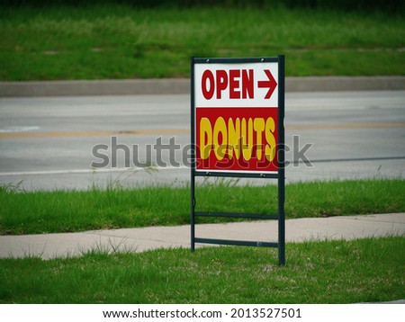 Streetside sign with directions to a donuts outlet