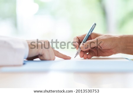 Elderly people signing with a doctor explaining the contract Royalty-Free Stock Photo #2013530753