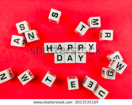The words Happy Day stand out among the alphabets and the red paper