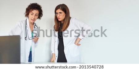 two female doctors examine medical tests on a laptop