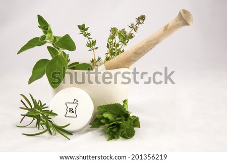 Homeopathic medicine concept of mortar and pestle containing fresh herbs with a prescription vial cap Royalty-Free Stock Photo #201356219