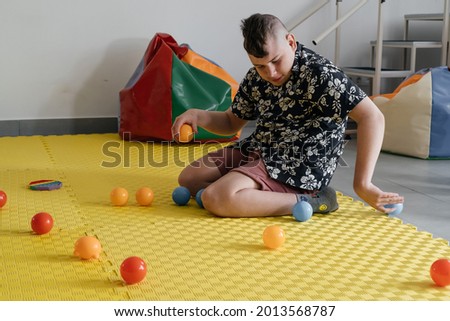 Children with disability getting sensory activity with toys, balls, small objects, cerebral palsy boy playing calming game, training fine motor skills. Rehabilitation center with therapist, mother Royalty-Free Stock Photo #2013568787