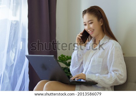 business woman typing on computer laptop and talk on telephone sitting on sofa,work from home concept