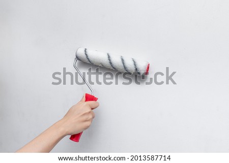 Applying primer and glue with a wide roller on the plastered surface of the wall for wallpapering Royalty-Free Stock Photo #2013587714