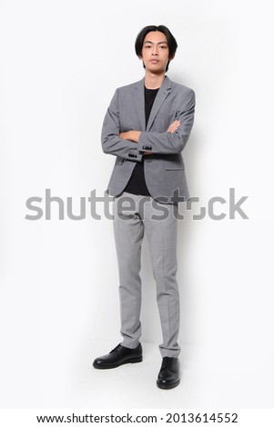 full body Portrait young businessman in gray suit black shirt, gay pants with arms crossed,in studio