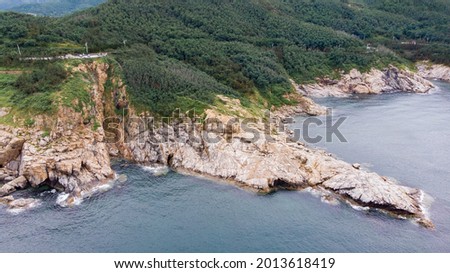 Aerial view of the rugged coastline along the Mao’tou Mountain in Wei’hai, Shan’dong Province, China. The photo was shot on a cloudy day in July.  Royalty-Free Stock Photo #2013618419