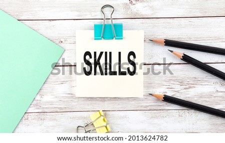 Stickers with pencils and notebook with text SKILLS on the wooden background