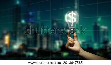 Double Exposure of Hand holding glowing light bulb with dollar sign inside and Night City background. Money making idea and Growth of dollar exchange rate Concept.