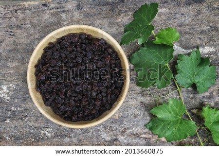 Dried black currant berries and green leaves grapes on wood table  background.
