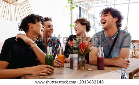 Fun group of friends laughing together in a restaurant. Four young queer people enjoying being together during lunch. Friends bonding and spending time together. Royalty-Free Stock Photo #2013682148