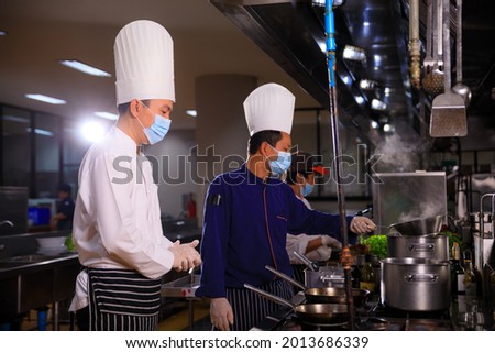 The male executive chef discussing the menu with his colleague in the kitchen.Food and restaurant concept. Royalty-Free Stock Photo #2013686339