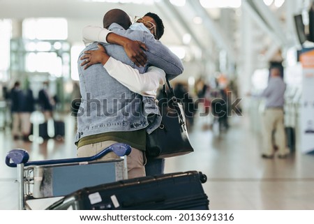 African couple met in airport after separation due to covid. Man and woman hugging each other at arrival gate at airport terminal. Royalty-Free Stock Photo #2013691316