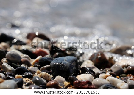 Wet pebble stones on blurred background of sea waves. Summer beach, vacation concept