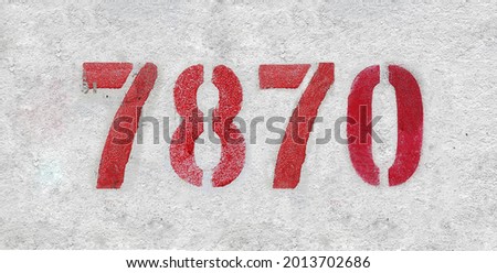 Red Number 7870 on the white wall. Spray paint. Number seven thousand eight hundred and seventy.