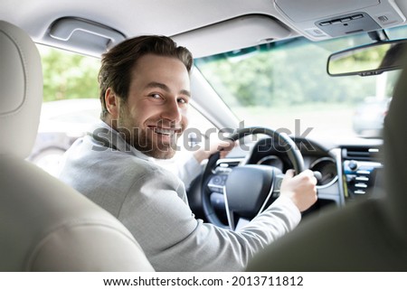 Lifestyle travel tourism positivity, transportation. Successful man sits at steering wheel of prestigious car. Portrait of handsome guy in suit, smiling driving auto, turns to passenger back seat Royalty-Free Stock Photo #2013711812