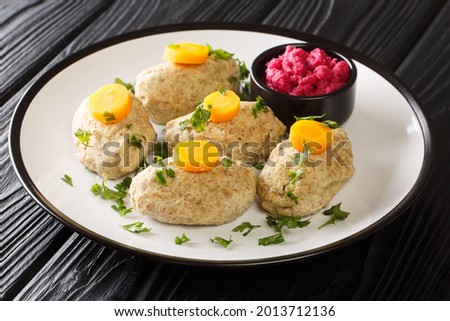 Delicious Jewish food Gefilte Fish Fishballs from river fish served with horseradish and carrots close-up in plate on the table. horizontal
