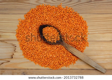 Red lentils on wooden table and spoon background. Vegetarian superfood. top view. Flat laying.