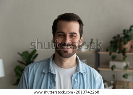Head shot bearded Caucasian cheery man. Handsome male smile look at camera standing alone in cozy domestic room. Successful individual entrepreneur professional occupation, single guy portrait concept