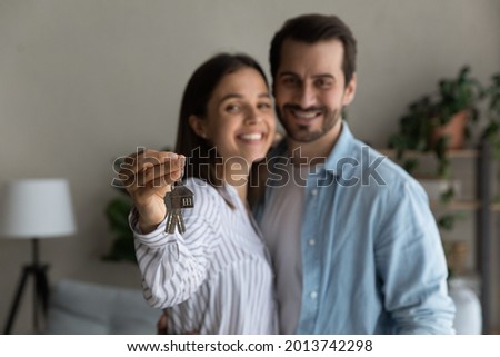 Happy married 30s couple smile look at camera, close up focus to keys bunch from newly bought house. Bank mortgage for young family, start new independent life at own home, housing improvement concept Royalty-Free Stock Photo #2013742298