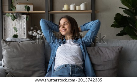 Attractive woman enjoy carefree weekend sit on comfy sofa with hands behind head looks away daydreams feels happy and untroubled breath fresh ventilated conditioned air. Leisure, modern home concept Royalty-Free Stock Photo #2013742385