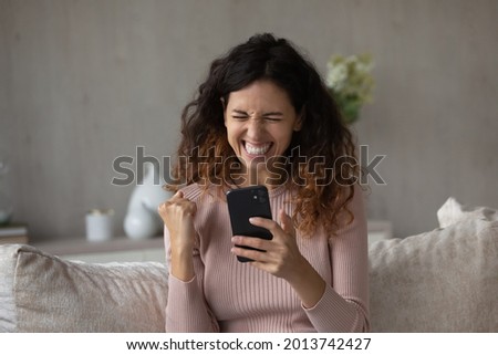 Overjoyed millennial Hispanic woman feel euphoric win online lottery on cellphone. Smiling young Latino female triumph read good news or get promotion notice on smartphone. Success concept. Royalty-Free Stock Photo #2013742427