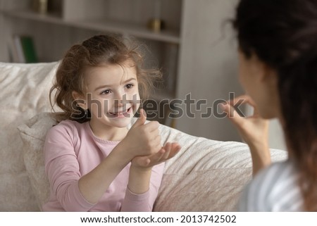 Small ethnic girl child make hand gesture talk with mom use sign language. Smiling little biracial numb deaf disabled kid communicate with tutor or coach. Disability, nonverbal communication concept. Royalty-Free Stock Photo #2013742502