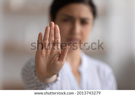 Close up focus on Indian woman showing stop gesture at camera, blurred background, strong young female protesting against domestic violence and abuse, bullying, saying no to gender discrimination Royalty-Free Stock Photo #2013743279