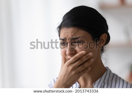 Close up of depressed frustrated Indian woman crying, feeling anxiety, upset sad young female feeling panic attack, covering face with hand, thinking about problems, suffering from migraine Royalty-Free Stock Photo #2013743336