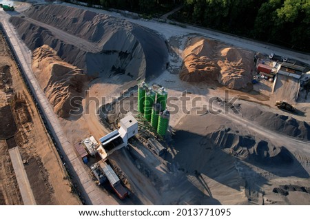 Ready mix concrete batching plant. Producing сoncrete and portland cement mortar for construction and formworks. Pouring concrete through to a ready-mixed truck. Drone view. Out of focus Royalty-Free Stock Photo #2013771095