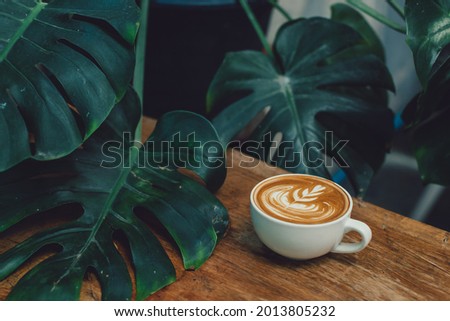 coffee cup latte art on wood bar with leaf in background  Royalty-Free Stock Photo #2013805232