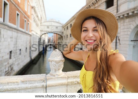 Happy young woman takes selfie photo in front of Venice Bridge of Sighs. Self portrait of beautiful girl in Venice, Italy.