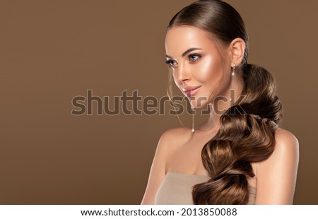 Beautiful girl . Fashionable and stylish woman in trendy jewelry big earrings .Curly ponytail hairstyle.  Fashion look  , beauty and style. Natural makeup and cosmetics Royalty-Free Stock Photo #2013850088