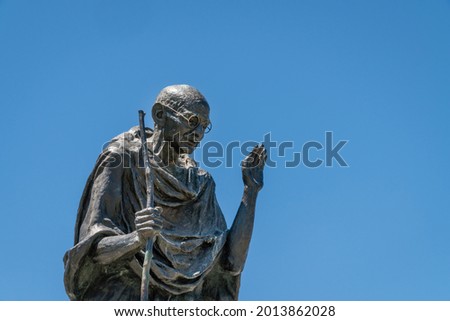 Statue of Mahatma Gandhi against bright blue background Royalty-Free Stock Photo #2013862028