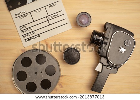 Movie clapper, film reel and camera on wooden background, top view