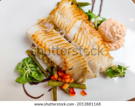 halibut fish fillet served on a bed of couscous and salad