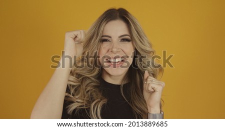Young beautiful Caucasian blonde girl happily. Success and achievement concept. Cheerful pretty blonde woman on yellow background.