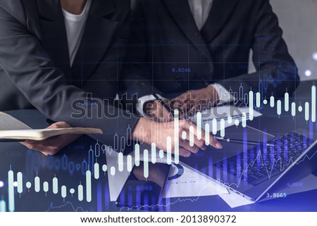 Two traders researching historic data to predict stock market behavior. Women in trading business concept. Forex and financial hologram chart over the table with the document.