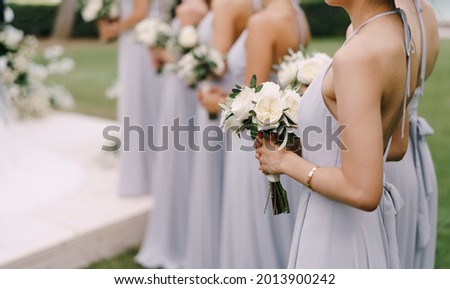 Bridesmaids in dresses stand with bouquets of flowers in a row Royalty-Free Stock Photo #2013900242