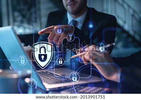 Two colleagues working together to protect clients confidential information and cyber security. IT hologram padlock icons modern office background at night time Royalty-Free Stock Photo #2013901751