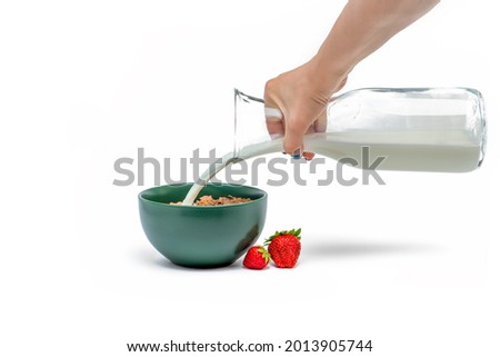 Cooking muesli, isolate on white background Woman pours milk from a jug into a saucer with muesli flakes. Large banner for print or advertising