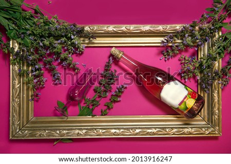 A creative composition with pink wine and a stylish glass of wine. sage flowers and an old vintage frame give the composition a special charm. Flat layout, top view, a place to copy.