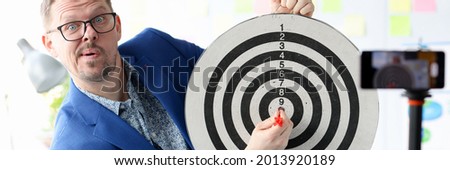 Young business coach hitting target in front of the mobile phone camera