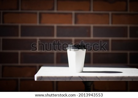 White disposable coffee cup on a white table