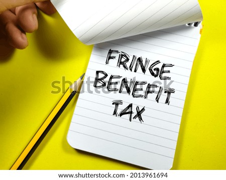 Business and benefit concept.Text FRINGE BENEFIT TAX writing on notebook with pencil on a yellow background.